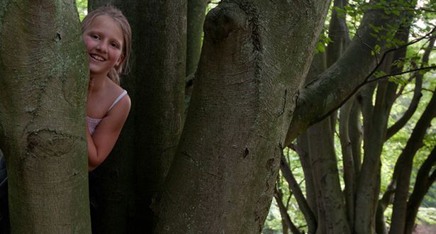 Ein kleines Mädchen versteckt sich hinter einem Baum im Marxener Paradies