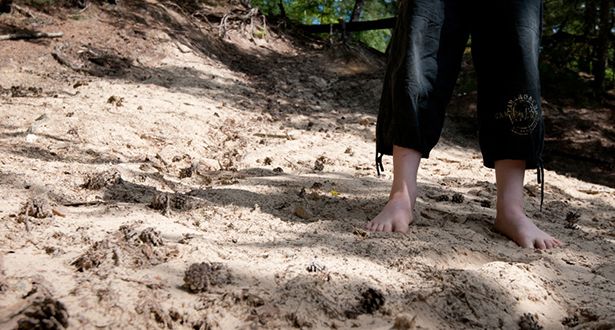 Detailausschnitt der nackten Füße eines kleinen Jungen der im Dünensand steht