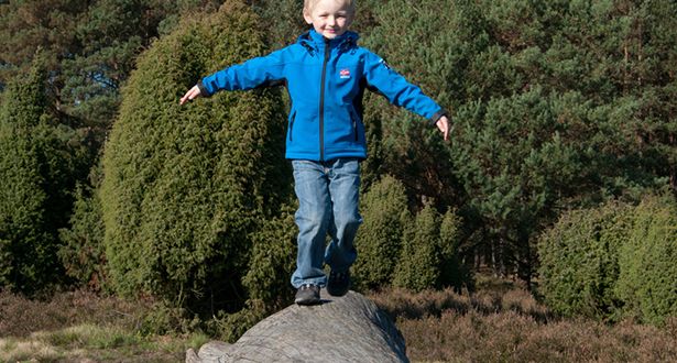 Ein kleiner Junge balanciert über einen Baumstamm