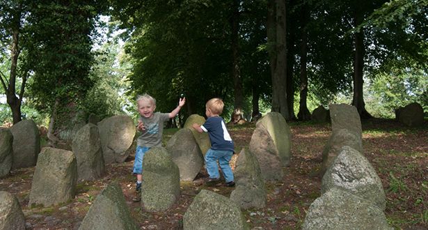 Zwei kleine Jungen spielen Fangen in mitten einer Gruppe von Steindenkmälern
